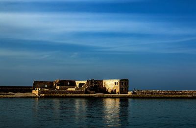 Buildings by sea against sky