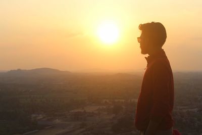 Side view of man looking at sunset