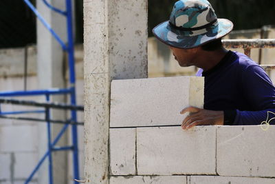 Side view of man standing against brick wall