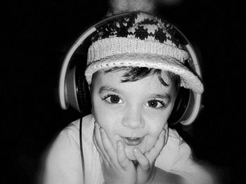 Portrait of boy listening to music through headphones against black background