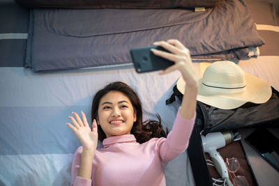 Young woman using mobile phone while sitting on bed at home