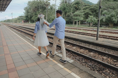 Rear view of people standing on railroad station platform
