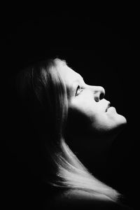 Close-up portrait of young woman against black background