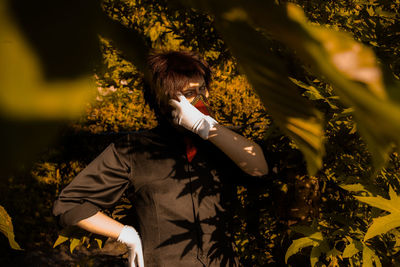 Portrait of young woman wearing mask standing by tree