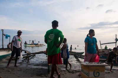 People working on beach against sky