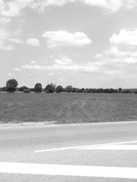 Road by field against sky