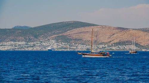 Sailboat sailing on sea against mountain