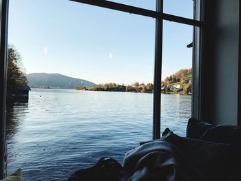 View of lake against sky seen through window