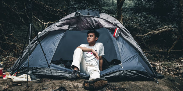 Portrait of young man sitting at tent