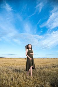 Woman standing in field against blue sky