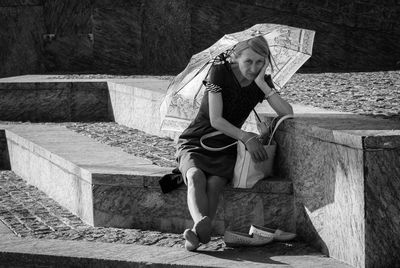 Full length of young woman sitting against wall