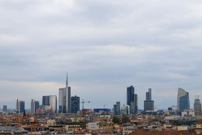 Buildings in city against cloudy sky