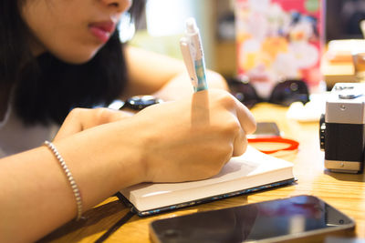 Close-up of a cropped woman writing in book