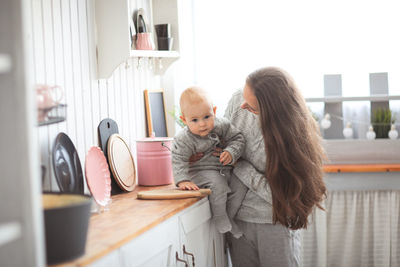 Side view of young woman using mobile phone while standing at home