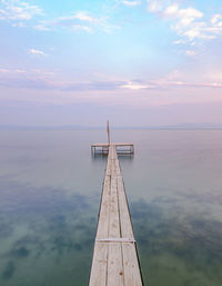 Pier over sea against sky during sunset