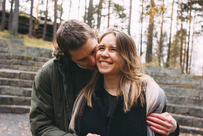 Smiling couple embracing against trees