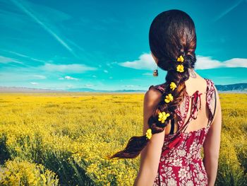 Rear view of woman standing on field against sky