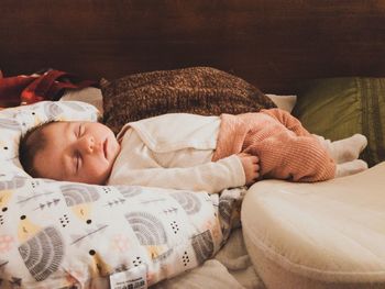 Close-up of baby girl sleeping on bed at home