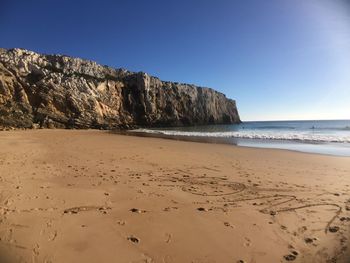 Scenic view of beach against clear blue sky