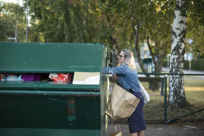 Blond woman throwing rubbish into waste bin