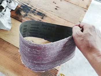 Cropped hand holding paper on wooden table