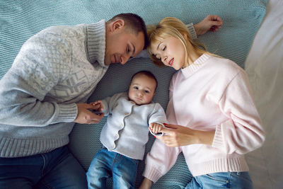 Family with son lie on the bed next to the christmas tree at home