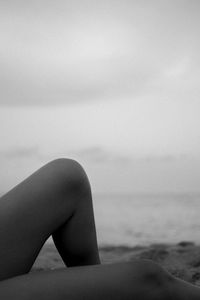 Woman sitting on beach against sky