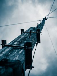 Low angle view of pole with steel cables against sky