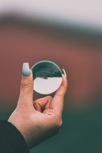 Close-up of hand holding a crystal sphere 