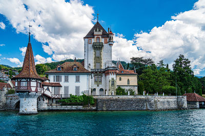 Buildings by river against sky