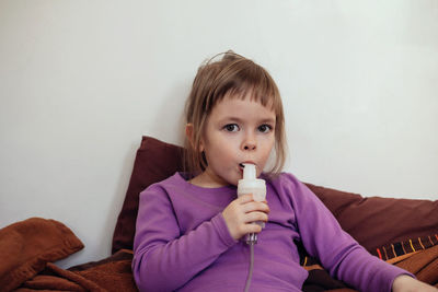 Sick child lies in bed and makes inhalation using a nebulizer.. treatment of cough with inhalation
