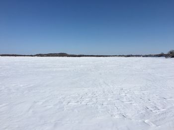 Snow covered landscape against clear blue sky