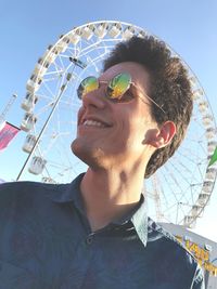 Low angle view of smiling young man against ferris wheel