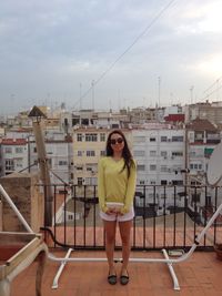 Portrait of young woman standing at harbor against sky