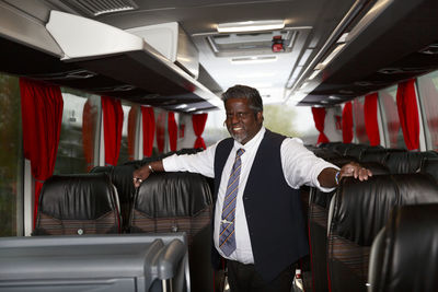 Smiling driver standing in bus