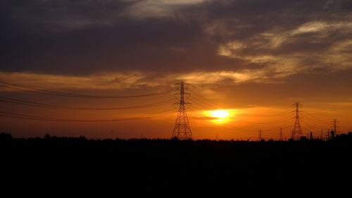 Silhouette electricity pylon against sky during sunset