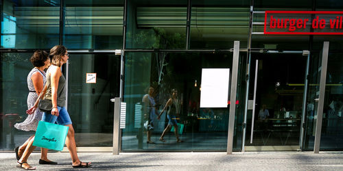 Woman walking on glass in city