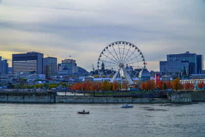 Ferris wheel by river against sky