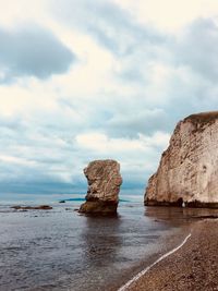 Rock formation on beach against sky