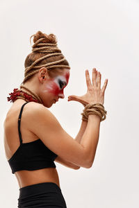 Portrait of young woman with arms raised against white background