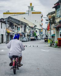 Rear view of man riding bicycle on street