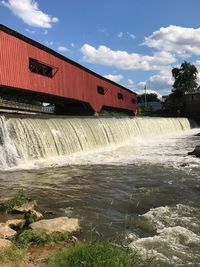 Built structure by dam against sky