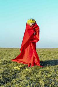 Red umbrella on field against sky