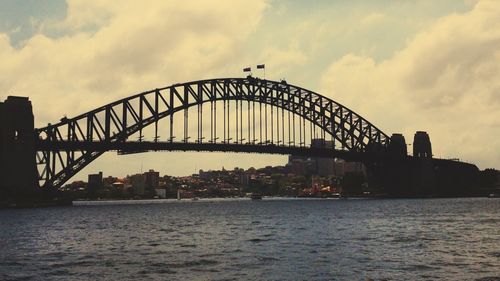 Bridge over river against sky in city