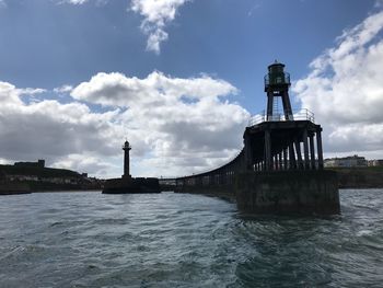 Lighthouse by sea against sky