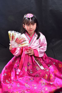 Portrait of cute girl with pink standing against black background
