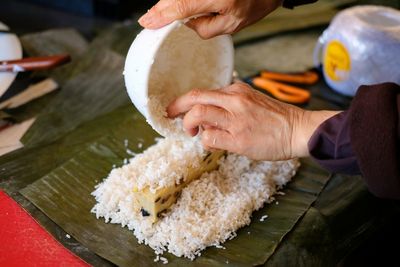 Close-up of person preparing food on banana leaf