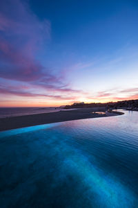 High angle view of infinity pool by beach at sunset