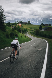 Woman riding her roadbike on road in the austrian alps under dramatic sky