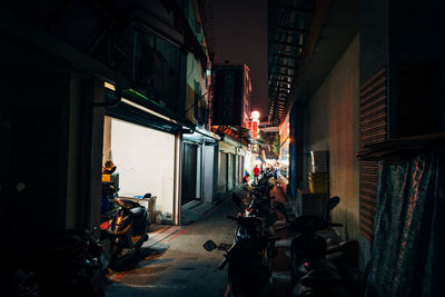 Vehicles in alley amidst buildings at night